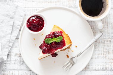 Cheesecake berry sos ve Beyaz ahşap masa arka plan üzerinde kahve ile dilim. Tablo üstten görünüm. Kafede Kahvaltı, kahve saati