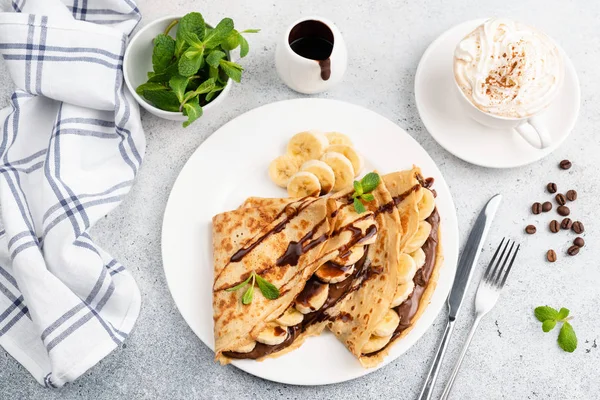 Crepes con plátano, chocolate y taza de capuchino — Foto de Stock