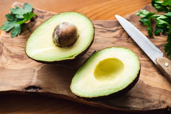 Two avocado halves on wooden cutting board — Stock Photo, Image