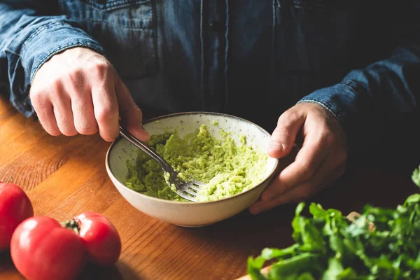 Man mashing avocado in bowl