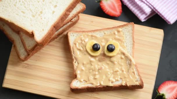 子供の学校の昼食のための面白い怒っている鳥の顔とピーナッツバタートーストを作るのモーションアニメーションを停止 — ストック動画