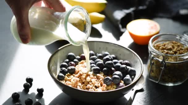 Het Gieten Van Melk Kom Met Muesli Bosbessen Zwarte Lijst — Stockvideo