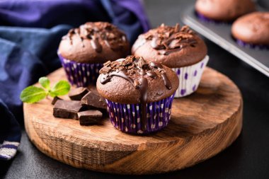 Chocolate muffins on wooden serving board clipart