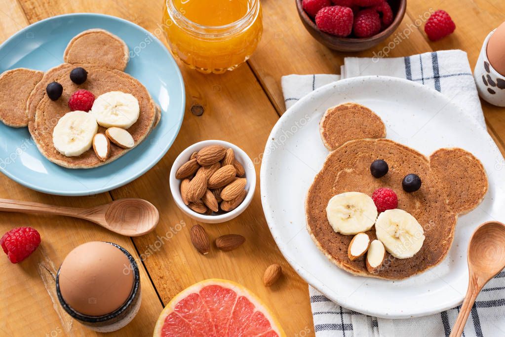 Kids breakfast with pancakes and fruits on a wooden table