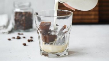 Yavaş hareket buz kahve küpleri ile cam içine süt dökme. Ferahlatıcı yaz soğuk içecek