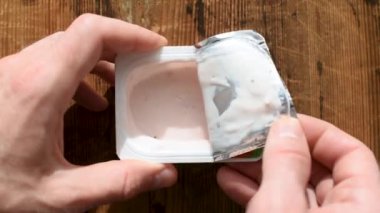 Açılış yoğurt kavanozu. Adam meyveli yoğurt plastik kavanoz açar