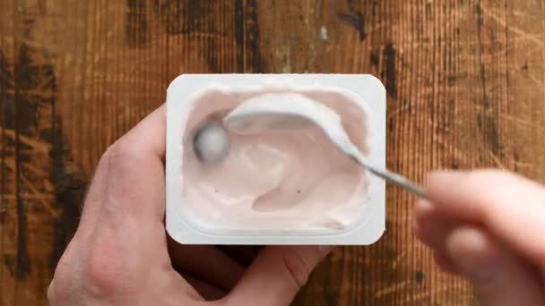 随着时间的推移 吃塑料罐中的蓝莓酸奶 古色古香的表格背景 顶部视图 — 图库视频影像