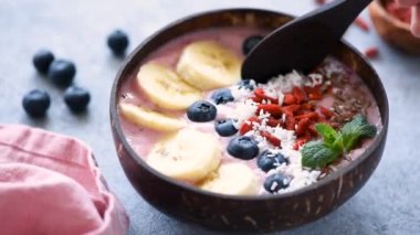 Yeme sağlıklı gıda acai smoothie kase muz, goji çilek, keten tohumu, yaban mersini ve hindistan cevizi gevreği ile tepesinde. Yakın çekim görünümü, yavaş çekim görüntüleri