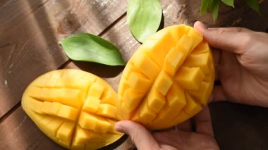 Kişi ahşap masa arka plan üzerinde kesme mango açar, closeup görünümü. Sağlıklı gıda, sulu tropikal meyve