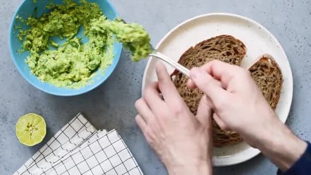 在全谷物面包上撒上捣碎的鳄梨 制作健康的早餐吐司 — 图库视频影像