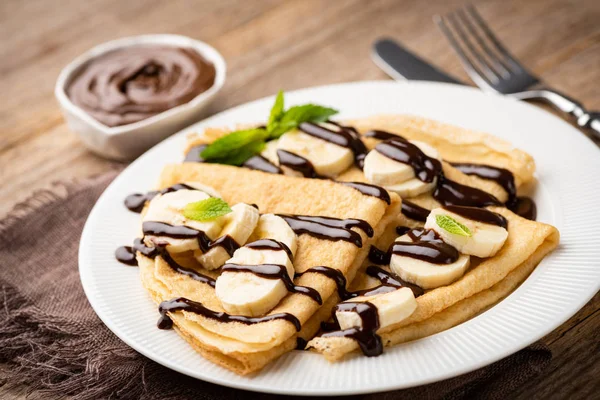 Crepes com molho de chocolate e bananas na placa branca — Fotografia de Stock