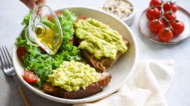 Sağlıklı vejetaryen avokado tost hizmet vermektedir. Kahvaltı açık yüz sandviç püresi avokado ile üzerine sızma zeytinyağı dökün