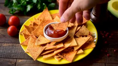 Domates sosuna mısır ekmeği cipsi batıran kişi. Tex mex veya geleneksel Meksika çerez gıda