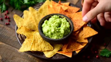 Erkek el guacamole içine mısır cipsi nachos daldırma. Meksika yemeği, atıştırmalık veya meze yemek