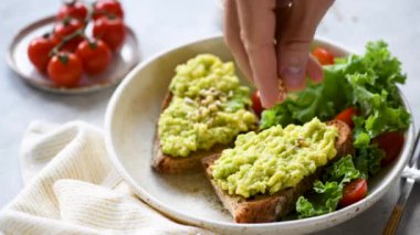 Kişi sağlıklı bir vejetaryen kahvaltı için tohumile avokado tost garnitür