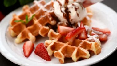 Dondurma, çilek ve çikolatalı Belçika waffle 'ı yemek. Tatlı yemek, tatlı. Şişmanlatıcı, sağlıksız yeme konsepti