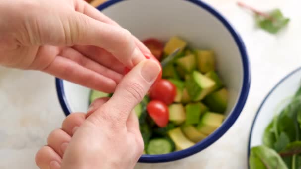 チェリートマトとサラダ アボカド キュウリ 女性シェフが野菜サラダボウルにチェリートマトを追加 — ストック動画