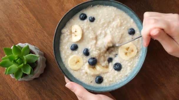 Mangiare Porridge Farina Avena Con Banana Mirtilli Mani Donna Mescolando — Video Stock