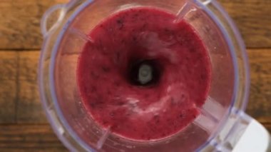 Blender 'da yabanmersinli Acai meyveli smoothie' nin yavaş çekimde karıştırılması, üst manzara. Sağlıklı çiğ vegan gıda konsepti