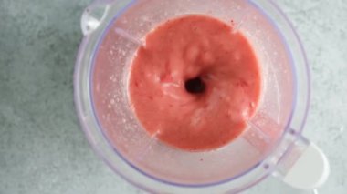 Çilekli smoothie blender 'da yavaş çekimde karıştırılıyor. Kırmızı pembe vejetaryen smoothie ile blender iç görünümü
