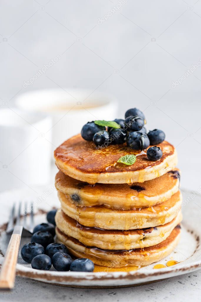 Blueberry pancakes with honey on plate. Stack of fluffy pancakes. Tasty sweet breakfast food