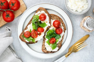 Ricotta peyniri, kavrulmuş vişneli domates ve bir tabakta doğranmış fesleğen. İtalyan yemeği. Üst görünüm