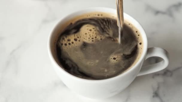 Mélanger le café noir chaud avec une cuillère. Tasse de café sur table en marbre
