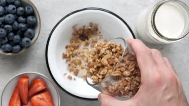 Kahvaltıda granola kasesi. Sağlıklı kahvaltı gevrekleri yavaş çekimde yulaf ezmesi ballı granola kaseye düşüyor.