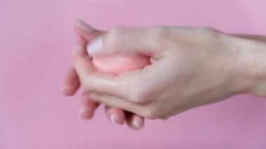 Pembe arka planda pembe sabunla kadın ellerini yıkıyor. Temizleme, bakteri önleme prosedürü