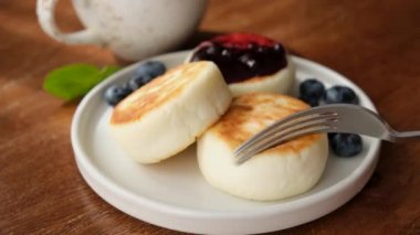 Yabanmersini reçelli süzme peynirli börek. Sağlıklı kahvaltıda yaban mersini soslu cheesecake yemek. Rus, Ukrayna mutfağı yemekleri