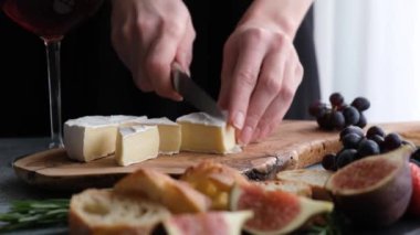 Peynirli, peynirli, incirli ve üzümlü. Peynir yapmak için peynirli camembert kesen kadın.