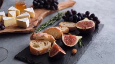 Peynir tabağı, camembert peyniri, taze incir, siyah üzüm, baget ve bir bardak kırmızı şarap. Çeşit çeşit peynir ve şarap.