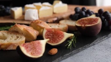 Peynirli, peynirli, peynirli, incirli, baget ve üzümlü. Kadın eli ile peynir dilimi seçiyor. Şarap aperatifleri.