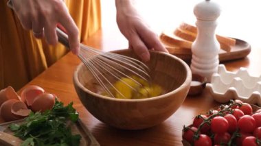 Tahta kasede kablo çırpıcısıyla yumurta karıştırmak. Kadın kahvaltıda omlet ya da omlet hazırlar.