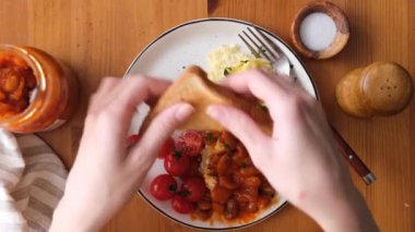 Çırpılmış yumurta ve fırında fasulye kahvaltısı. Omlet yiyen bir kadın kahvaltıda fırında fasulye ve kızarmış ekmek yiyor.