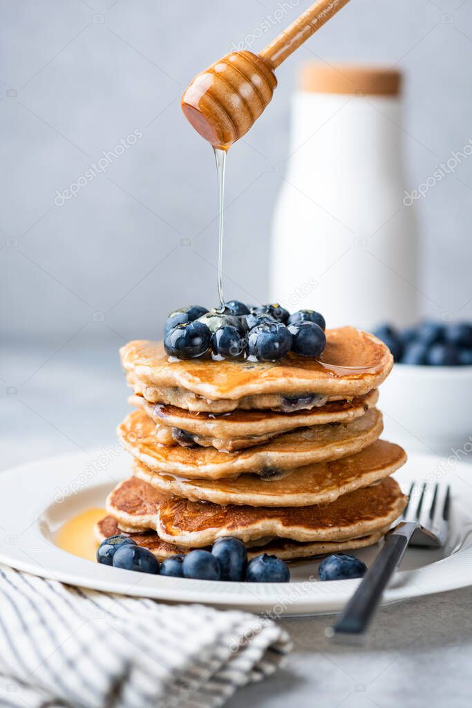 Honey pouring on stack of blueberry pancakes
