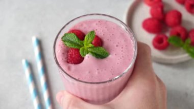 Bardakta ahududu püresi. Erkek eli masaya bir bardak pembe dut kokteyli koydu.