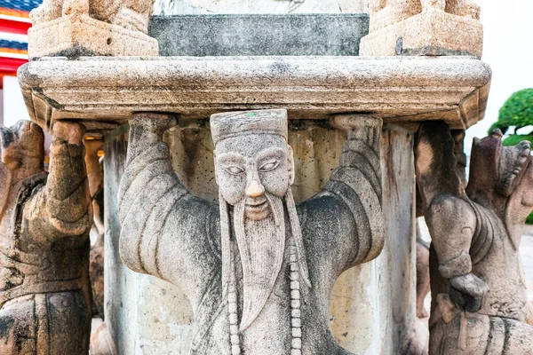 The statue of a beard holding a stone base at Wat Pho, Pho temple,  `Temple of the Reclining Buddha` Bangkok Thailand.