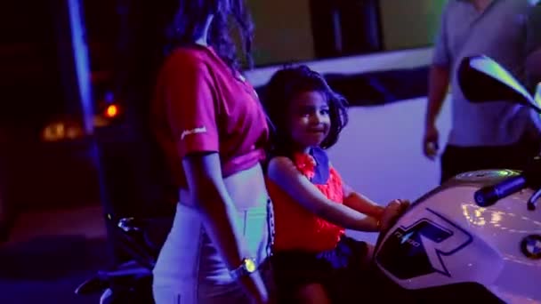 Малыш сидит на выпущенном в 2017 году велосипеде BMW, в то время как модель стоит рядом с ней - Пуна, Индия - 14 апреля 2017 года — стоковое видео