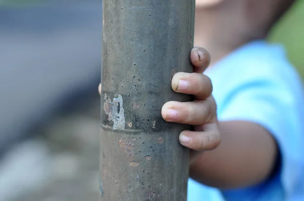 A toddler is holding an iron pole
