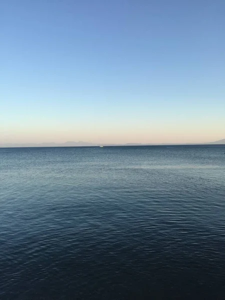 Mare calmo mare e barca in lontananza al tramonto — Foto Stock