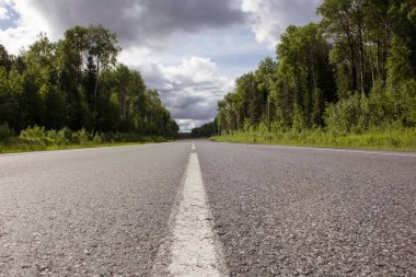 Ormandan geçen bir köy yolunun iz ve pürüzsüz asfaltı. Çift yönlü yol, gelen şeritte sollama gerektirir.