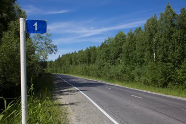 Yolun başlangıcında. Uzun bir yolculuğun ilk kilometresinin işareti iki şeritli bir otoyolun kenarında duruyor.