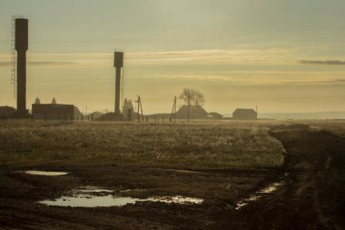 Şafakta çiftlikte. Şafak ve sis, çiftliğin ana hatlarını, su kulelerini, tarlaları ve ahırları gizliyor