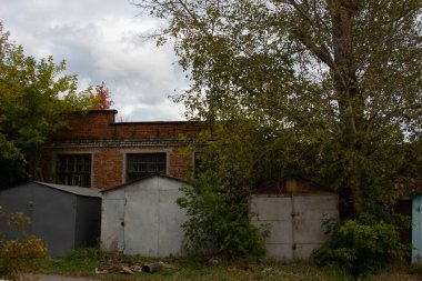 Bahçenin köşesindeki eski metal garajlar. Ağaçların altındaki eski avlunun köşesindeki özel metal garajlar.