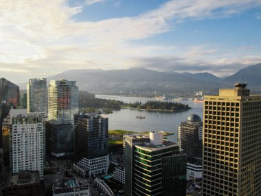 Yukarıdan Vancouver şehir merkezi binaları Stanley Park, arka planda deniz ve dağlar.
