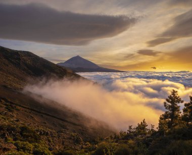 Batan güneşin bulutların arasında gözlük. Günbatımı Teide Volkanı Milli Parkı içinde. 