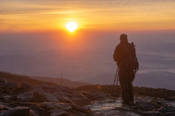 person photographing sunrise on top of mountain