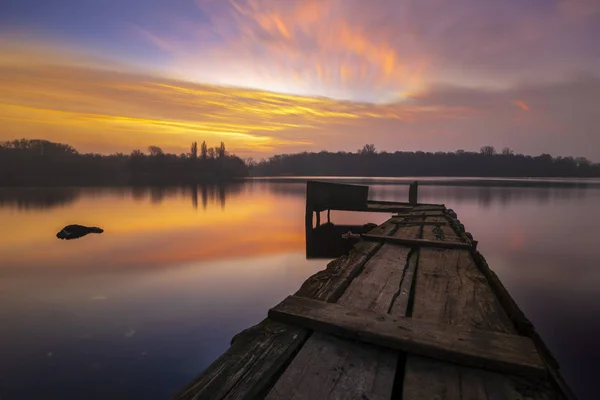 Alter, hölzerner Steg am See bei schönem Sonnenaufgang — Stockfoto
