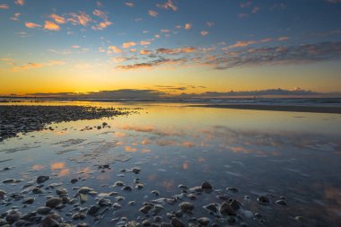 Baltık Denizi güzel gündoğumu, sonra fırtına taşlı beach